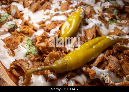 Eine Nahaufnahme der berühmten schwedischen Kebab-Pizza zeigt ihre kräftigen Aromen, mit grünen Fefferoni-Paprika und cremiger Knoblauchsoße, die ihre reichhaltige und süße küche bereichert Stockfoto