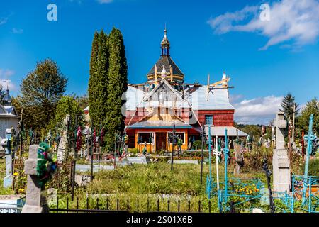 Ein Friedhof mit einem großen roten Gebäude im Hintergrund. Das Gebäude hat ein blaues Dach und ein blaues Kreuz oben Stockfoto