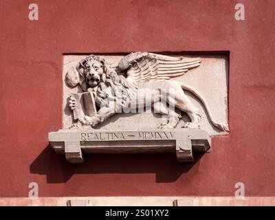 VENEDIG, ITALIEN - 06. MAI 2015: Gedenktafel mit geflügeltem Löwen auf einer roten Gipswand Stockfoto