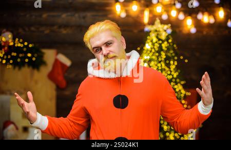 Frohe Weihnachten und frohes neues Jahr. Lächelnder Weihnachtsmann im Zimmer, das zu Weihnachten eingerichtet wurde. Hübscher bärtiger Mann im Weihnachtsmannkostüm, Porträt. Familienspaß Stockfoto