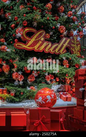 Zürich, Schweiz - 24. November 2024: Ikonischer Lindt-Weihnachtsbaum am SBB Hauptbahnhof Zürich mit roten Ornamenten und Schokoladendekorationen Stockfoto