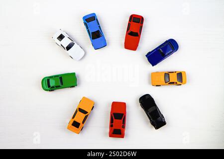 Farbenfrohe Spielzeugautos im Kreis auf weißem Hintergrund, leuchtende Miniaturfahrzeuge, verspielt und lustig, ideal für Kinderspielzeug, pädagogische Tasche Stockfoto