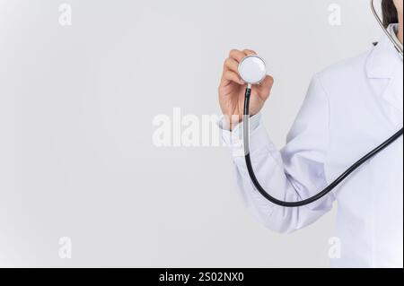 Eine Nahaufnahme einer Ärztin, die ein Stethoskop vor der Kamera zeigt, auf einem weißen Atelierhintergrund. Bild mit einem Kopierraum, medizinische Versorgung, Krankenhaus Stockfoto