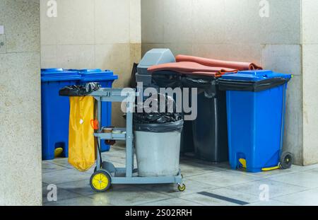 Reinigungswagen an einem öffentlichen Ort mit Reinigungsprodukten: Mopp, Eimer zur Bodenreinigung, Besenlöffel, Haushaltschemikalien, Haushaltslappen Stockfoto