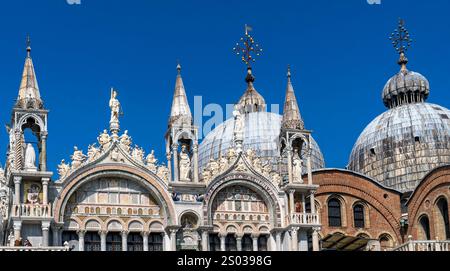 Die prunkvolle Architektur des Markusdoms in Venedig mit seinen Kuppeln und Türmen vor einem klaren blauen Himmel. Stockfoto