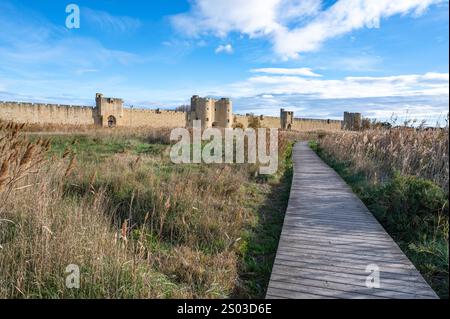 Die südlichen Mauern von Aigues-Mortes in der Camargue, von einer Promenade aus gesehen, die die Salins de Midi säumt Stockfoto