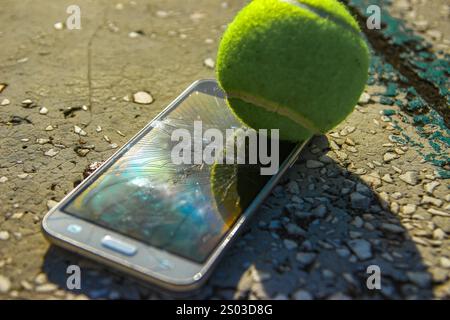 Handy beschädigt während eines Tennisspiels auf einem Tonplatz, zertrümmertes Telefonglas zertrümmert vom Ball Stockfoto
