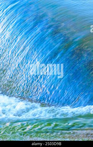 Eine große Welle, die ins Ufer stürzt und das Wasser spritzt und in die Luft spritzt. Die Szene ist dynamisch und kraftvoll, wobei das Wasser einen erzeugt Stockfoto