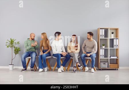 Verschiedene junge Menschen sitzen zusammen, diskutieren über Arbeit oder Studium, tauschen gemeinsam Ideen aus. Stockfoto