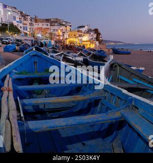 Blaue Fischerboote am Strand in der Abenddämmerung im Dorf Taghazout, Marokko. Dezember 2024 Stockfoto