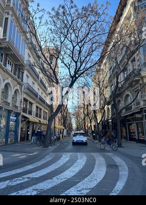 Rue pittoresque à Valence, Espagne, bordée d’arbres et d’immeubles historiques avec Balcons en fer forgé. Scène typique d’une ville européenne animée. Stockfoto