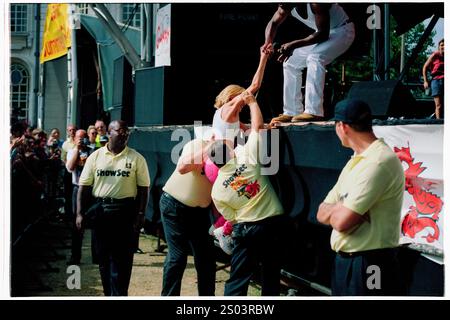 DANNII MINOGUE, KONZERT, 1995: Concert Security Helfen Sie einem jungen Dannii Minogue auf der Bühne, während er am 12. August 1995 beim Cardiff Big Weekend Festival auf dem Museum Rwns in Cardiff, Wales auftritt. Foto: ROB WATKINS. INFO: Dannii Minogue ist eine australische Sängerin, Schauspielerin und TV-Persönlichkeit, die für ihre Pop-Hits und ihre dynamische Karriere bekannt ist. Die jüngere Schwester von Kylie Minogue erlangte Bekanntheit durch Songs wie I Begin to Wonder und als Jurymitglied am X Factor. Stockfoto