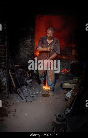 Ein Gießereiarbeiter in einer Werkstatt in Alexandria, Ägypten, der geschmolzenes Metall während eines Gießprozesses gekonnt handhabte. Ein großes Gründerbild Stockfoto