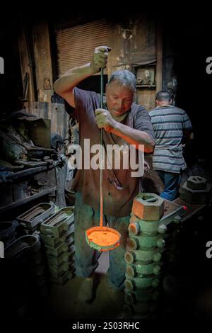 Ein Gießereiarbeiter in einer Werkstatt in Alexandria, Ägypten, der geschmolzenes Metall während eines Gießprozesses gekonnt handhabte. Ein großes Gründerbild Stockfoto