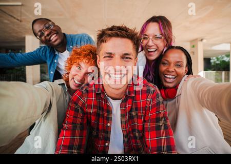 Eine fröhliche Gruppe verschiedener Teenager-Schüler macht gemeinsam ein Selfie, lächelt hell in die Kamera, genießt Freundschaft, Lachen und lustige Momente. Junge multirassische Freunde lachen, die vorne starren. Hochwertige Fotos Stockfoto