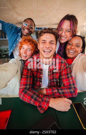 Vertikal. Fröhliche Gruppe von verschiedenen Teenagerstudenten, die zusammen ein Selfie machen, hell in die Kamera lächeln, Freundschaft und lustige Momente genießen. Junge multirassische Freunde lachen, die vorne starren. Hochwertige Fotos Stockfoto