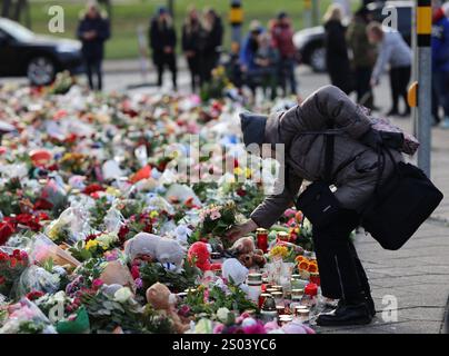 Magdeburg, Deutschland. Dezember 2024. Die Trauernden stehen vor der Johanniskirche, der zentralen Gedenkstätte nach dem Angriff auf den Magdeburger Weihnachtsmarkt, und legen Blumen. Selbst am Heiligabend, vier Tage nachdem ein Auto auf dem Weihnachtsmarkt in eine Menschenmenge gefahren ist, geht die Trauer und Bestürzung weiter. Quelle: Matthias Bein/dpa/Alamy Live News Stockfoto