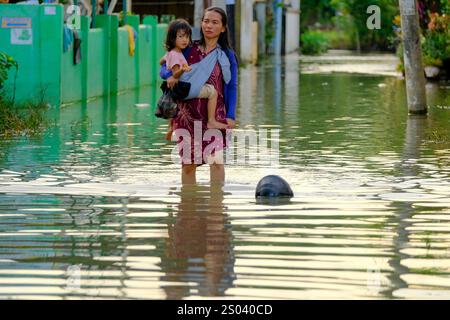 Makassar, Indonesien. Dezember 2024. Eine Frau, die ein Mädchen hält, geht durch das Hochwasser, nachdem am 24. Dezember 2024 ein heftiger Regen Makassar, Provinz Süd-Sulawesi, Indonesien, getroffen hatte. Überschwemmungen und Erdrutsche haben in der vergangenen Woche mehrere Regionen des südostasiatischen Archipels getroffen. Quelle: Niaz Sharief/Xinhua/Alamy Live News Stockfoto