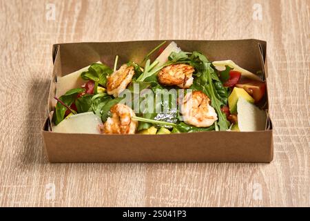 Eine Kiste zum Mitnehmen mit einem frischen Salat aus Garnelen, gemischtem Gemüse und Parmesankäse. Stockfoto
