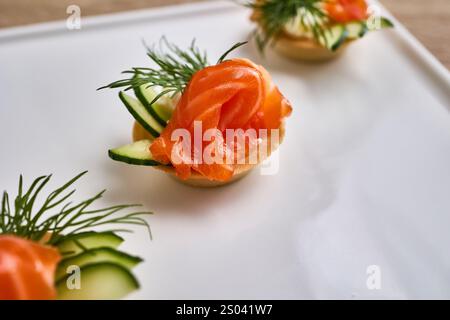 Mini-Tartlets gefüllt mit Frischkäse und garniert mit Räucherlachs, Gurke und Dill. Stockfoto