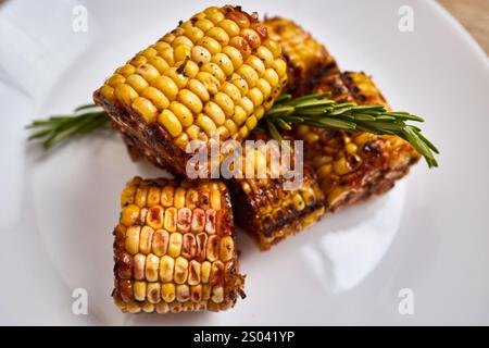 Zuckermaiskolben werden perfekt gegrillt und mit duftenden Kräutern abgeschmeckt. Stockfoto