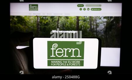 In dieser Fotoabbildung hält eine Person ein Handy mit dem Logo der niederländischen Umweltstiftung Fern vor der Webseite. Stockfoto