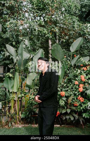 Ein südostasiatischer Mann, der warm lächelt, während er geradeaus blickt und einen fröhlichen und freundlichen Ausdruck ausstrahlt Stockfoto