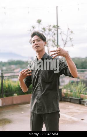 Südostasiatischer Mann, der eine Handgeste mit kühnem Ausdruck macht. Fokus auf Hand und Gesicht, Außenbereich, Tageslicht. Rebellion, Haltung Stockfoto