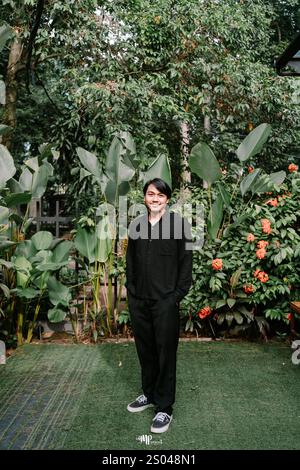 Ein südostasiatischer Mann, der warm lächelt, während er geradeaus blickt und einen fröhlichen und freundlichen Ausdruck ausstrahlt Stockfoto