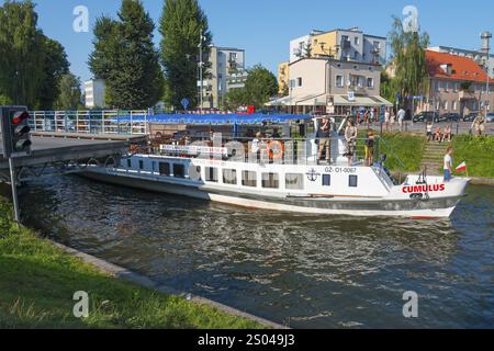 Weißes Schiff auf einem Kanal unter einer Brücke bei sonnigem Wetter, Boot Cumulus auf Kanal zwischen dem Kisajno-See und dem Niegocin-See, Schaukelbrücke, Gizycko, Warminsko- Stockfoto