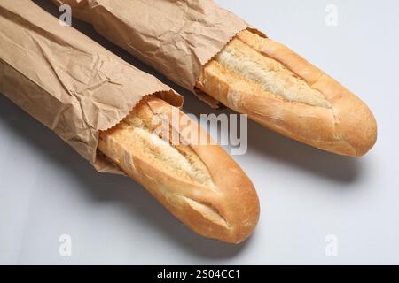 Papiertüten mit frischen Baguettes auf weißem Hintergrund, Nahaufnahme Stockfoto