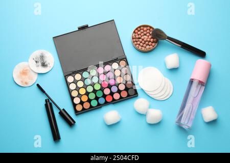 Flache Lay-Komposition mit Wattepads und Make-up-Produkten auf hellblauem Hintergrund Stockfoto