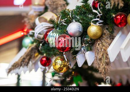 Eine detaillierte Nahaufnahme eines wunderschönen Weihnachtsbaums, der mit bunten Kugeln und eleganten Bändern für die Weihnachtszeit geschmückt ist Stockfoto