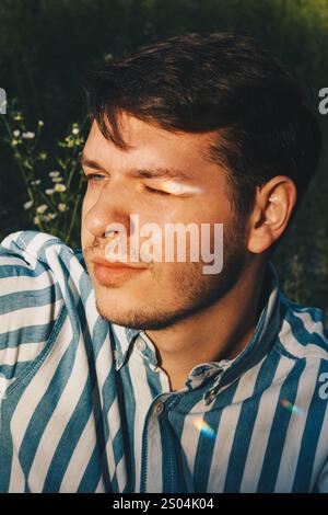 Ein detailliertes Porträt eines Mannes mit dunklen Haaren und gestreiftem Hemd, hervorgehoben durch eine Kulisse aus weißen Gänseblümchen. Die lebendigen Blumen bringen Harmonie und nat Stockfoto