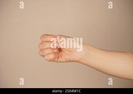 Eine hochgezogene geballte Faust hebt sich von einer hellen Wand ab und symbolisiert Stärke und innere Stärke. Der neutrale Hintergrund lenkt die Aufmerksamkeit auf den Entscheid Stockfoto