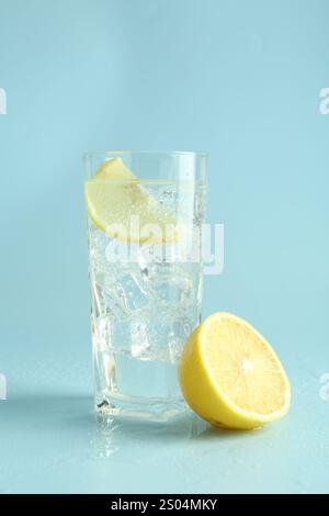 Limonadenwasser mit Zitronen- und Eiswürfeln im Glas auf hellblauem Hintergrund Stockfoto