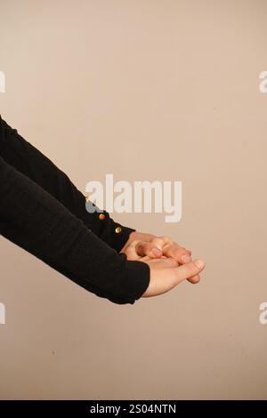 Zwei Hände greifen ihre Finger zu einer geschlossenen Haltung. Diese kraftvolle Geste zeigt Solidarität und Engagement. Vor neutralem Hintergrund, t Stockfoto