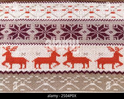 Strickmuster mit Schneeflocken, Hirsch, Blumen, gebrochenen Streifen. Orangefarbene, rotbraune, weiße, beige Wollfäden. Volkskunst. Warmer Winterpullover gestrickt Stockfoto