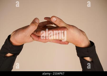 Zwei Hände greifen ihre Finger zu einer geschlossenen Haltung. Diese kraftvolle Geste zeigt Solidarität und Engagement. Vor neutralem Hintergrund, t Stockfoto