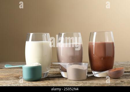 Verschiedene leckere Proteincocktails in Gläsern und Pudern auf Holztisch Stockfoto