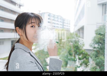 Eine junge Geschäftsfrau, die eine E-Zigarette raucht Stockfoto