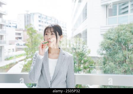 Eine junge Geschäftsfrau, die eine E-Zigarette raucht Stockfoto