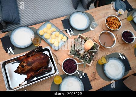 Gänsebraten zum Weihnachtsfest Blick auf einen festlich gedeckten Tisch. Im Mittelpunkt steht der Gänsebraten. Der Ursprung dieses Gänsebratens geht auf die Martinsgans zurück, die oft am Gedenktag des hl. Martin, noch vor Beginn des Advents gegessen wurde. Der Advent hatte früher den Charakter einer Fastenzeit. Mit der Christmette endete diese, und so wurde eine Gans als Festtagsbraten zubereitet. Leer Niedersachsen Deutschland *** Gänsenbraten zu Weihnachten Blick auf einen festlich gedeckten Tisch der Fokus liegt auf Gänsenbraten der Ursprung dieser Gänsebraten geht auf die St. Martins-Gans zurück, die oft vorkam Stockfoto