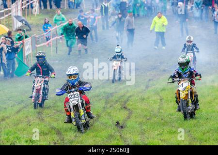 Ukraine, Romny, 2.-3. Juni 2018: Junge Motocross-Fahrer treten auf einer Grasstrecke während der ukrainischen Motocross-Meisterschaft an, umgeben von Zuschauern. Stockfoto