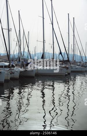 Eine ruhige Yachthafenszene mit Segelbooten, die sich in ruhigem Wasser spiegeln und faszinierende Muster erzeugen. Stockfoto