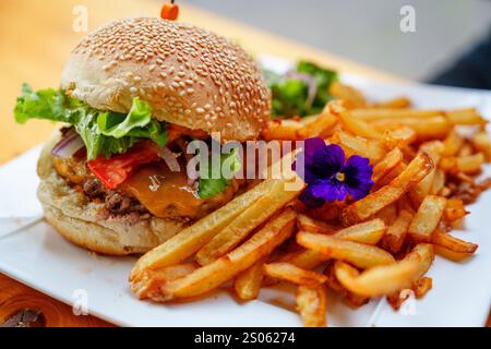 Köstlicher Burger und knusprige Pommes frites serviert auf einem weißen Teller in einem gemütlichen Diner in New York City Stockfoto