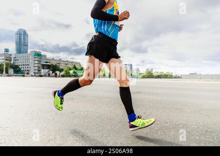 Läufer in Kompressionssocken und Ärmeln laufen Marathon auf der Straße Stockfoto
