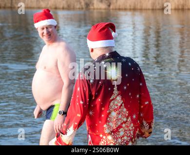 Berlin, Deutschland. Dezember 2024. Mitglieder des Vereins "Berliner Seehunde" gehen zum Weihnachtsschwimmen im Orankesee. Seit über dreißig Jahren kommen die Berliner Robben sonntags von Oktober bis April zum Eisschwimmen in den Orankesee – die Höhepunkte sind das Weihnachtsschwimmen und der Eisschwimmen-Karneval. Quelle: Paul Zinken/dpa/Alamy Live News Stockfoto