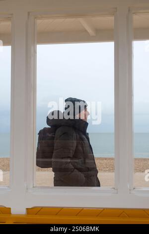 Porträt des Menschen an der Küste, durch ein Fenster gesehen, Wintermantel Stockfoto