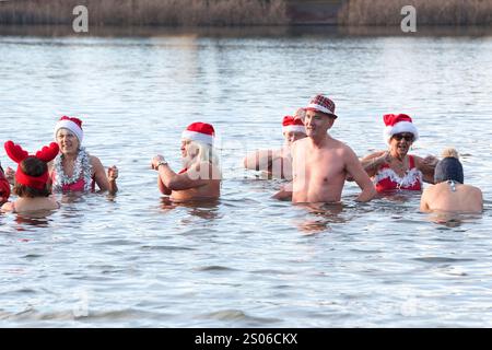 Berlin, Deutschland. Dezember 2024. Mitglieder des Vereins "Berliner Seehunde" schwimmen zu Weihnachten im Orankesee. Seit über dreißig Jahren kommen die Berliner Robben jeden Sonntag von Oktober bis April zum Eisschwimmen in den Orankesee – die Höhepunkte sind das Weihnachtsschwimmen und der Eisschwimmen-Karneval. Quelle: Paul Zinken/dpa/Alamy Live News Stockfoto